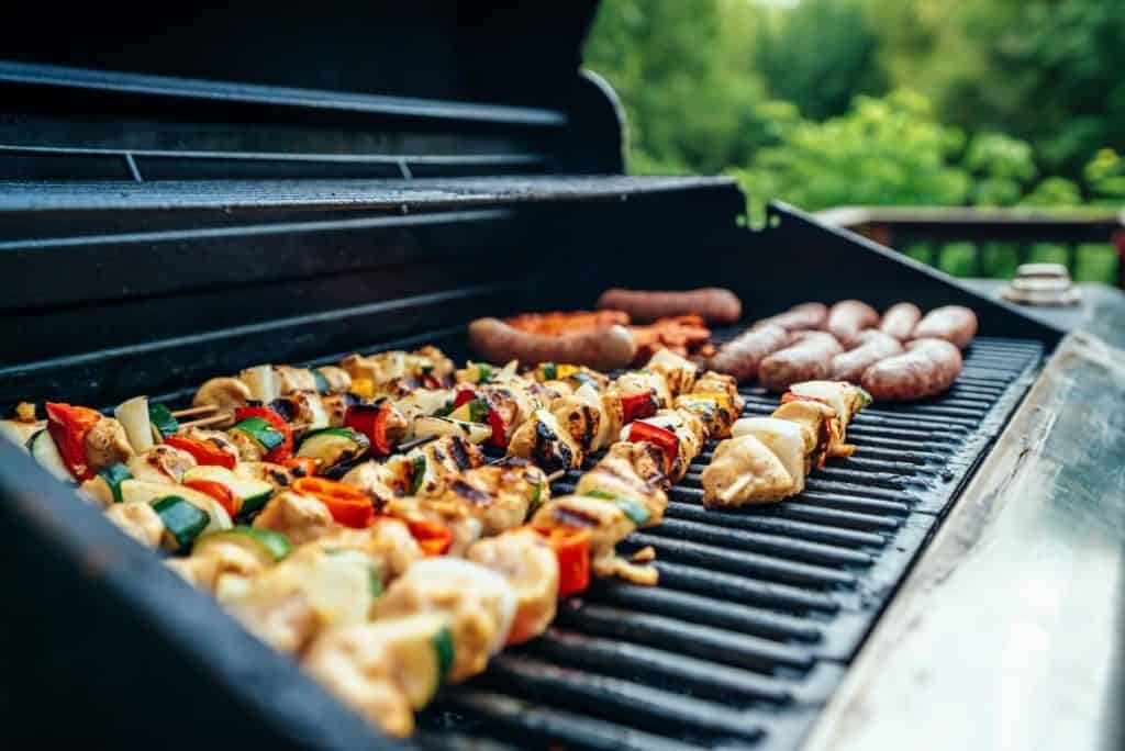 Chicken skewers and sausages being grilled