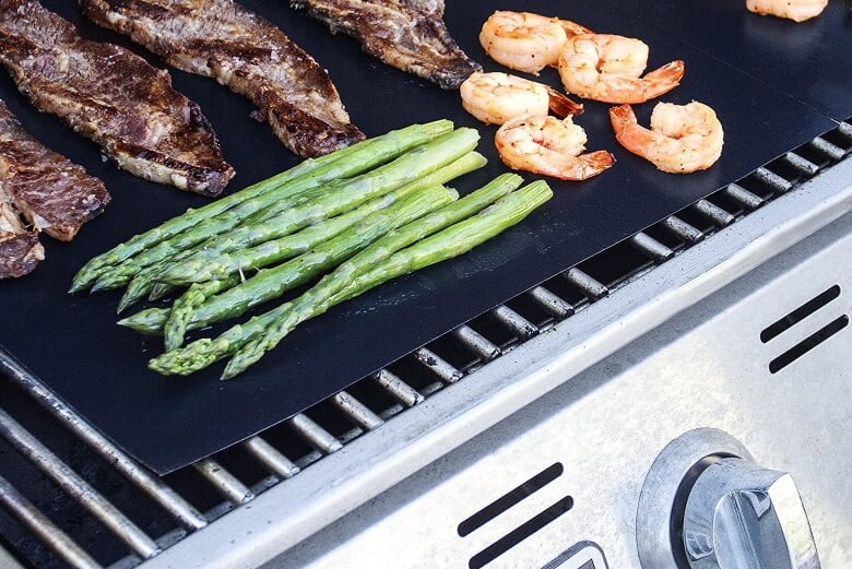 Aspargus, shrimps and steaks being grilled on Kitchen + Home grill mat