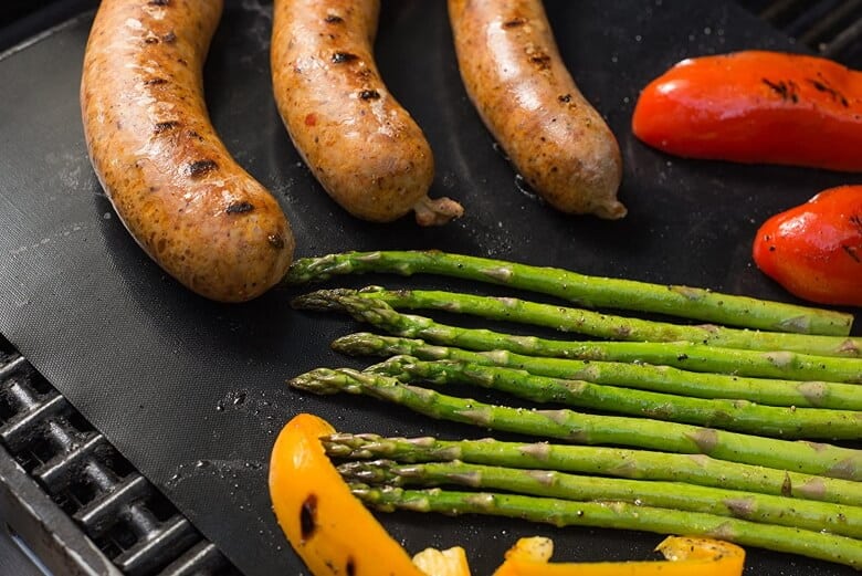 Sausages, aspargus and red and yellow peppers being grilled on a Twisted Chef grill mat