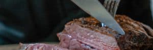 A piece of meat being cut with a knife and fork